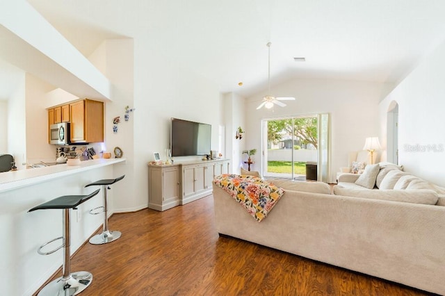 living room with arched walkways, high vaulted ceiling, wood finished floors, and visible vents