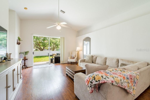 living area featuring arched walkways, lofted ceiling, visible vents, dark wood-type flooring, and a ceiling fan