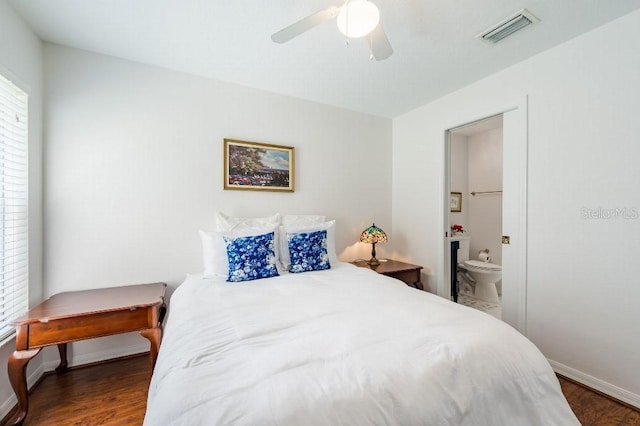 bedroom featuring baseboards, visible vents, a ceiling fan, ensuite bath, and wood finished floors