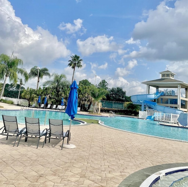 pool featuring a patio area, fence, and a water slide