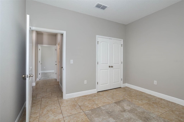 unfurnished bedroom with baseboards, a textured ceiling, visible vents, and a closet