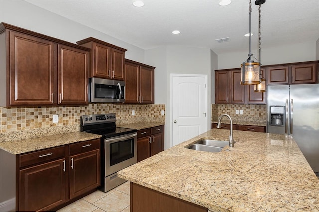 kitchen featuring visible vents, a sink, light stone countertops, stainless steel appliances, and backsplash