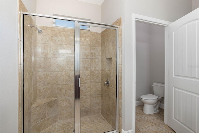 bathroom with toilet, a stall shower, tile patterned flooring, and baseboards