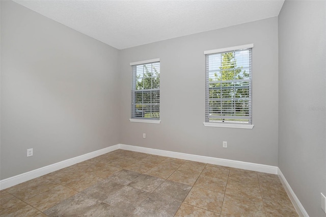 empty room featuring a textured ceiling and baseboards