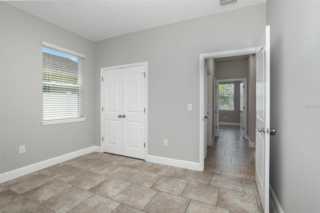 unfurnished bedroom with a closet, visible vents, and baseboards