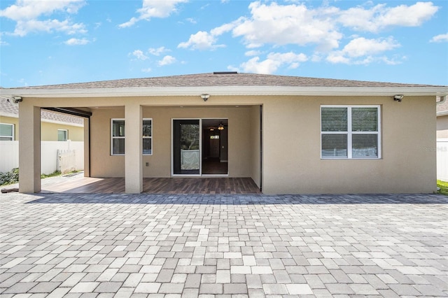 back of house featuring a shingled roof, fence, a patio, and stucco siding