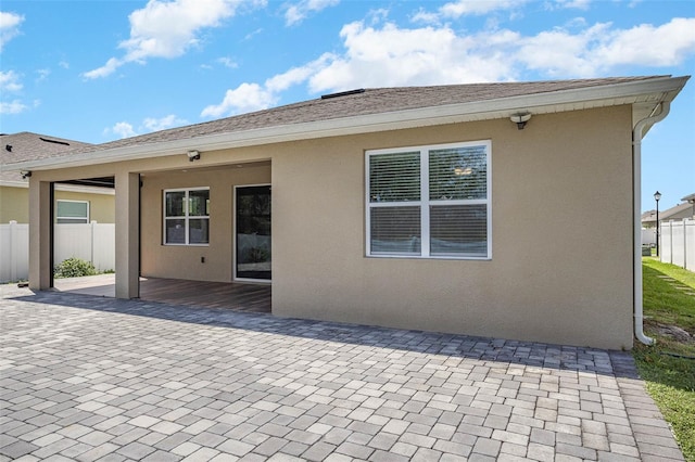 rear view of property featuring a patio area, a shingled roof, fence, and stucco siding