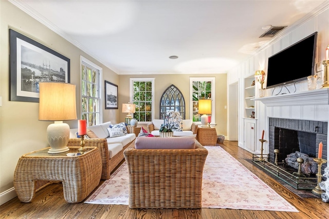 living room featuring hardwood / wood-style flooring, a fireplace, built in shelves, and ornamental molding