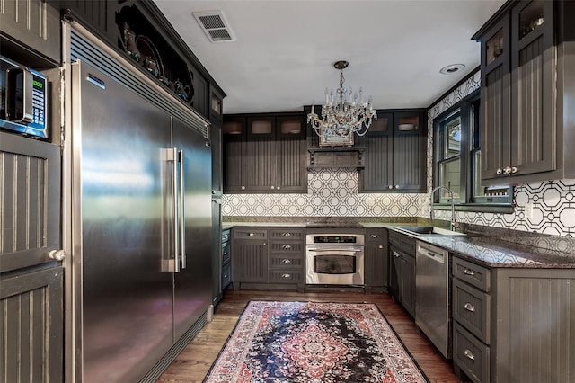 kitchen featuring sink, stainless steel appliances, dark wood-type flooring, and tasteful backsplash