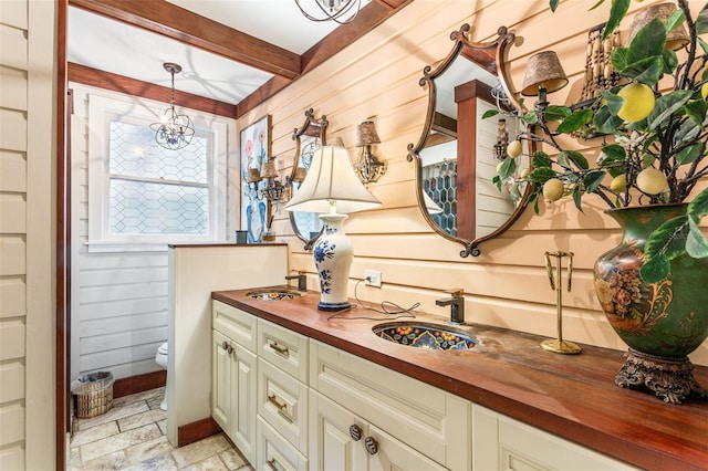 bathroom with beamed ceiling, toilet, vanity, and tile patterned floors