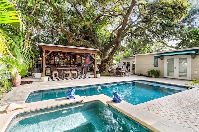 view of pool with a bar, french doors, and a patio