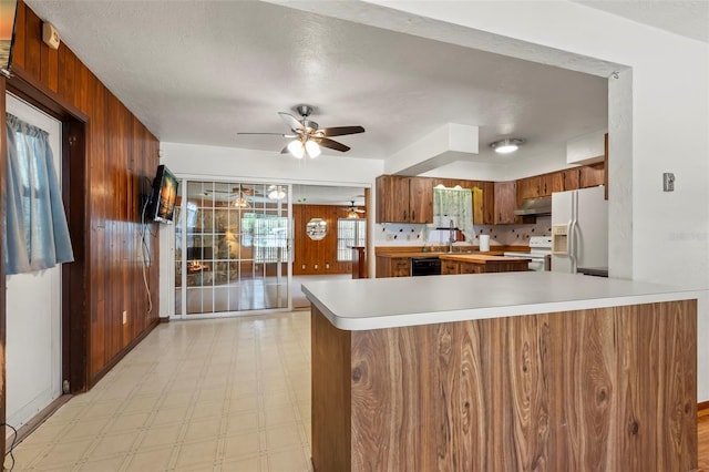 kitchen featuring white appliances, a textured ceiling, exhaust hood, ceiling fan, and kitchen peninsula