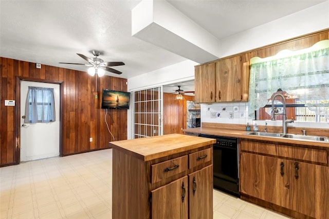 kitchen with butcher block counters, dishwasher, sink, light tile patterned floors, and ceiling fan