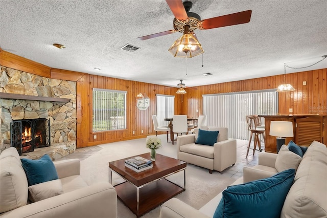 living room featuring ceiling fan, wood walls, light colored carpet, and a fireplace