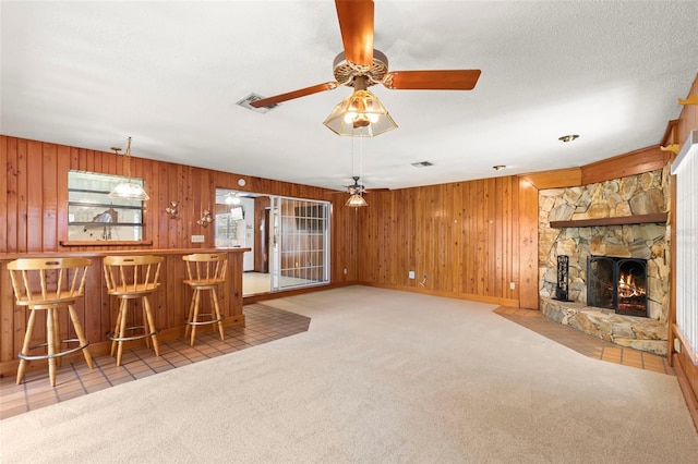 unfurnished living room with ceiling fan, light carpet, and wood walls