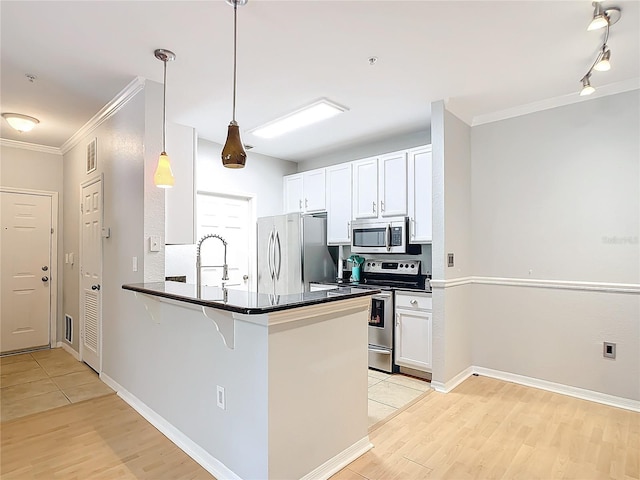 kitchen featuring appliances with stainless steel finishes, light tile patterned floors, hanging light fixtures, kitchen peninsula, and white cabinets