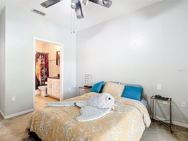 bedroom with ceiling fan, light carpet, and ensuite bathroom