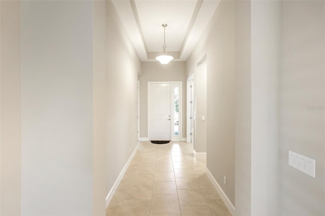 doorway to outside with a raised ceiling and light tile patterned floors