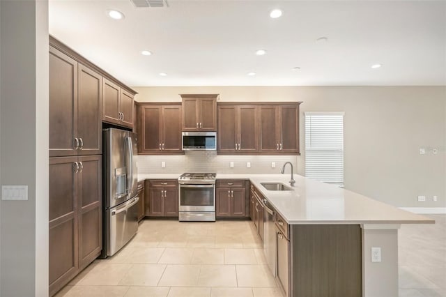 kitchen featuring appliances with stainless steel finishes, dark brown cabinets, sink, tasteful backsplash, and light tile patterned floors