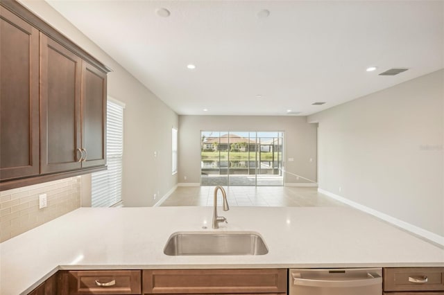 kitchen featuring stainless steel dishwasher, sink, and decorative backsplash