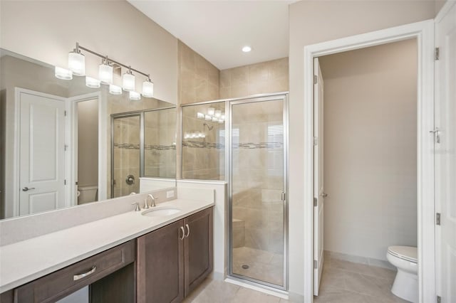 bathroom featuring tile patterned flooring, a shower with door, vanity, and toilet