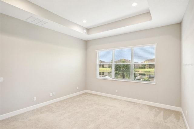 carpeted spare room with a tray ceiling