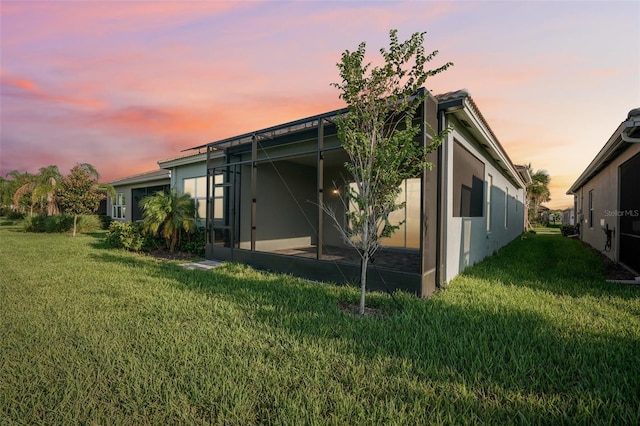 back house at dusk featuring a lawn