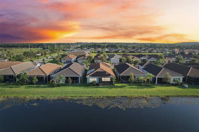 aerial view at dusk featuring a water view