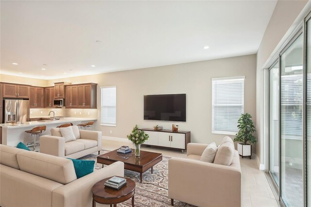 living room with sink, light tile patterned floors, and a healthy amount of sunlight