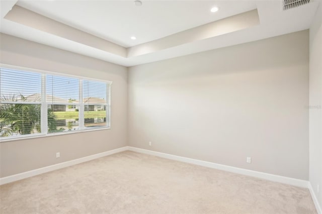 carpeted spare room featuring a tray ceiling