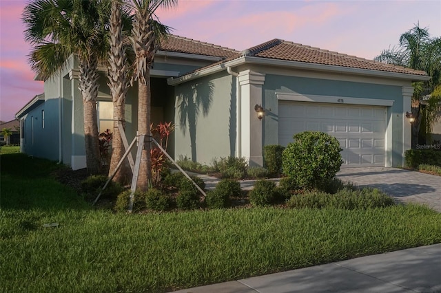 view of front of home with a garage and a lawn