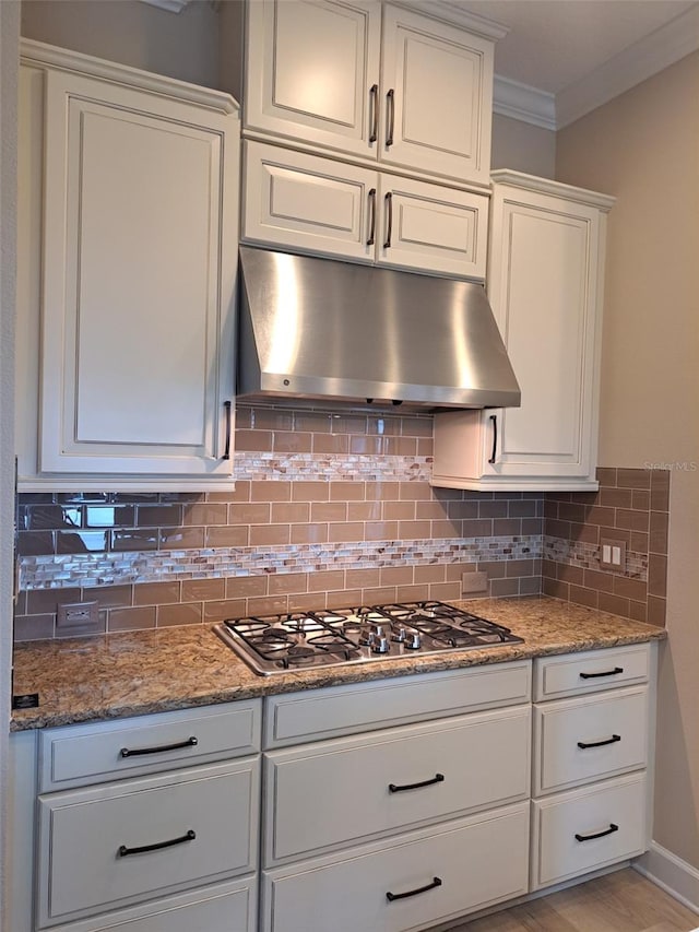 kitchen with stone countertops, backsplash, ornamental molding, light wood-type flooring, and white cabinetry