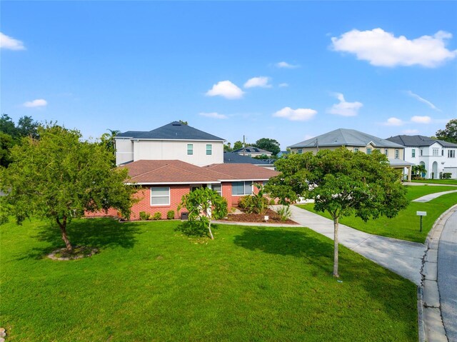 view of front of house featuring brick siding, a front lawn, and a residential view