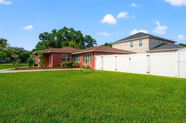 view of front of house featuring a front yard, brick siding, and fence