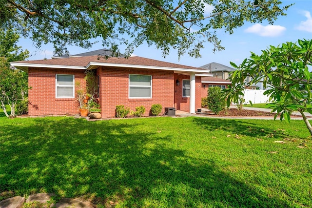 ranch-style house featuring fence, a front lawn, and brick siding