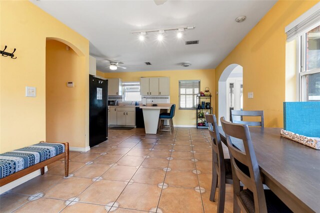 tiled dining area with ceiling fan and track lighting