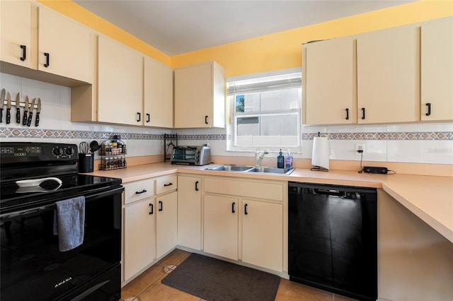 kitchen featuring tasteful backsplash, light countertops, cream cabinets, a sink, and black appliances