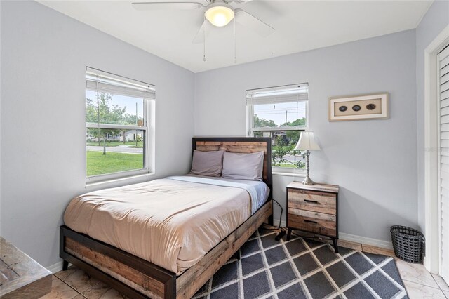 tiled bedroom featuring ceiling fan and multiple windows