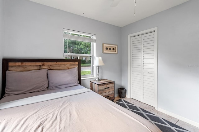 bedroom with ceiling fan, a closet, and tile patterned floors