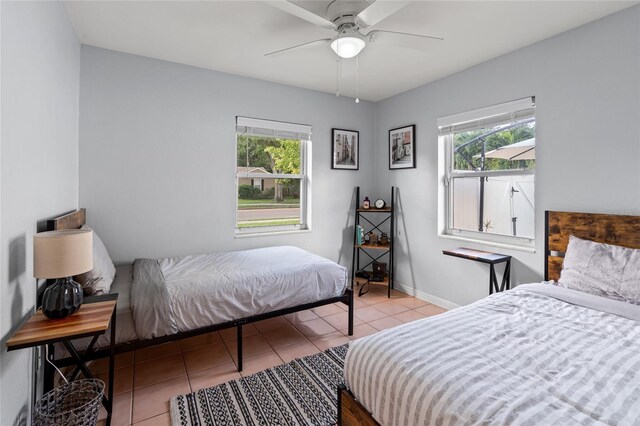 bedroom featuring light tile patterned floors, multiple windows, baseboards, and a ceiling fan