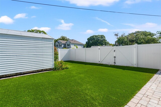 view of yard with a fenced backyard and a gate