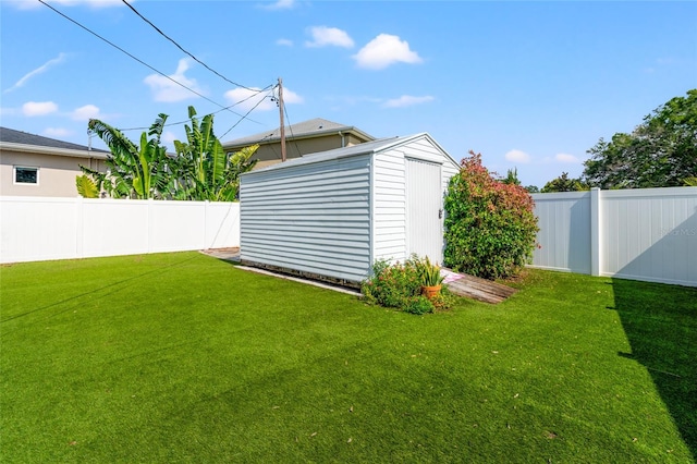 view of yard featuring a fenced backyard, a storage unit, and an outbuilding