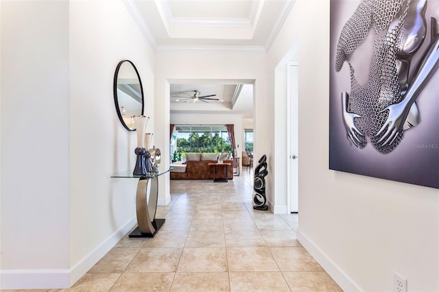 hallway with crown molding, a raised ceiling, and light tile patterned floors