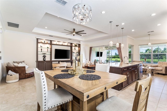 dining area with ceiling fan with notable chandelier, a raised ceiling, ornamental molding, and sink