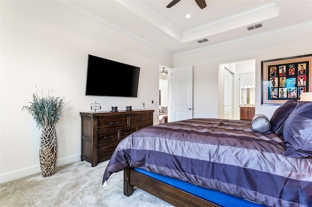 bedroom featuring ensuite bathroom, light colored carpet, a tray ceiling, ceiling fan, and ornamental molding