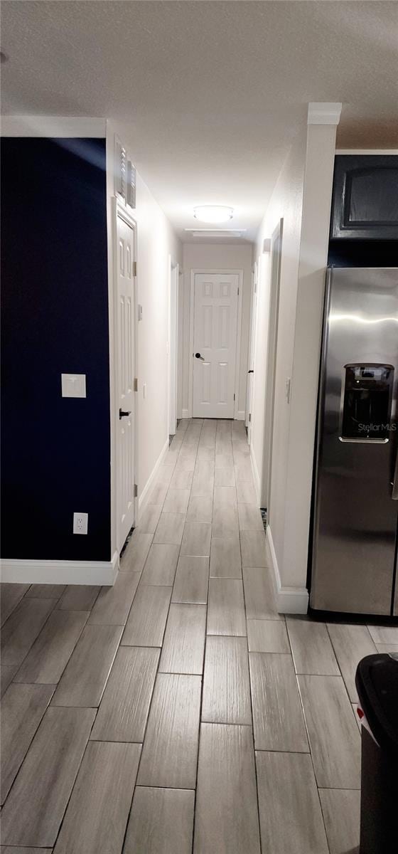 corridor featuring a textured ceiling and light wood-type flooring