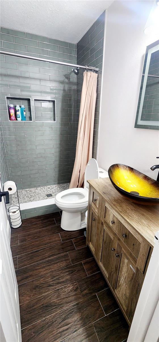 bathroom featuring vanity, curtained shower, toilet, and a textured ceiling