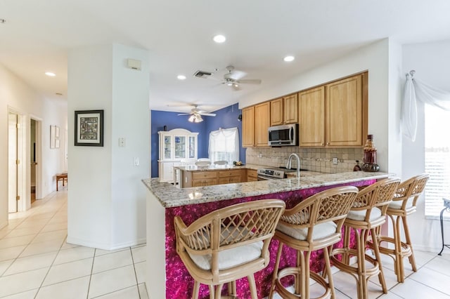 kitchen featuring appliances with stainless steel finishes, backsplash, kitchen peninsula, and plenty of natural light