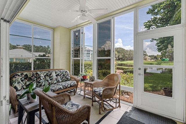 sunroom with ceiling fan and a water view