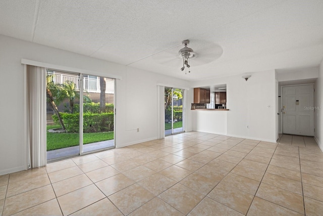 unfurnished room with ceiling fan, light tile patterned floors, and a textured ceiling